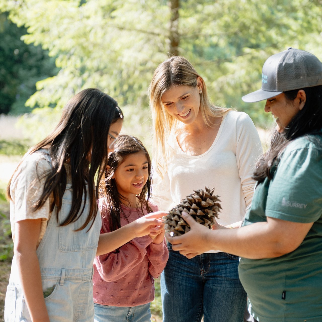 A family receiving a guided tour and viewing a large pinecone at the Surrey Nature Centre Ian Harland DSC 1332