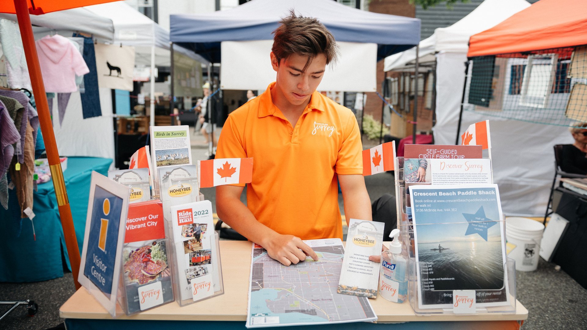 Visitor services rep shows location maps at the Cloverdale Market in Surrey BC Ian Harland DSC 3085